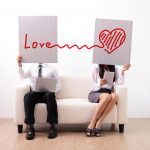 Frau und Mann halten Schilder vor das Gesicht mit Herz und Love