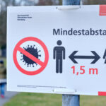 Schild mit Corona Abstandsregeln